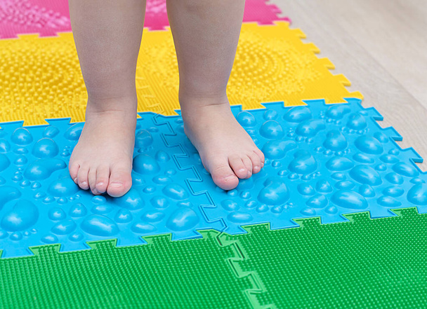 People. Children's small legs stand on multi-colored massage rugs. Health concept. Soft focus. Close-up - Photo, Image