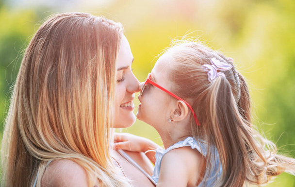 Family generation and people concept. Close-up portrait of smiling mother hugging cute little daughter. Little daughter hugging her happy mother. - 写真・画像