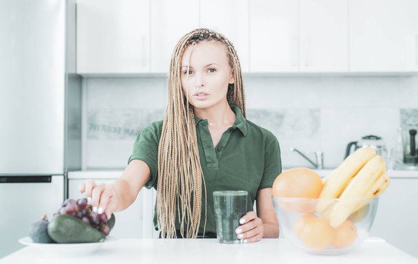 Вегетарианская диета. Улыбающаяся молодая женщина пьет зеленый смузи на кухне. Зеленый сок. Веганская диета дома. Диетическое питание. Естественный антиоксидант. Потеря веса
. - Фото, изображение