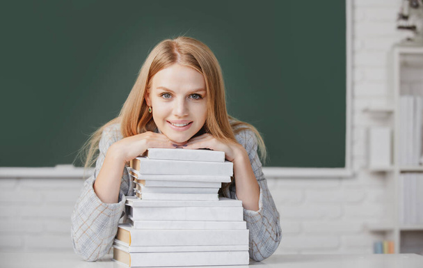 Portrait of female university student study lesson at school or university. Close up portrait of happy attractive young woman student with books on blackboard in classroom. - Фото, изображение