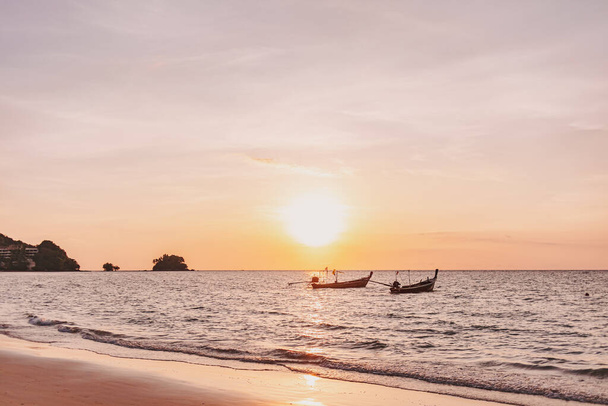 Sunset of Mai Khao Beach in Phuket Thailand with two local long tail boats. - Fotó, kép