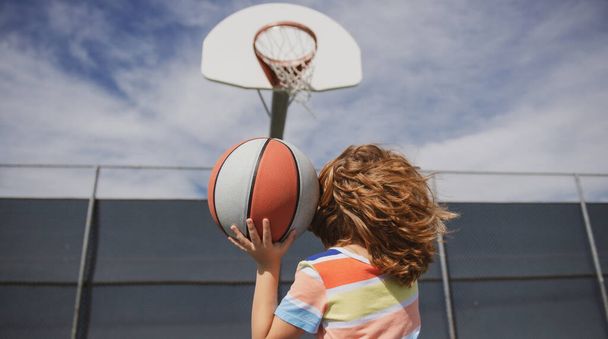 Cute little boy holding a basket ball trying make a score. - Фото, изображение