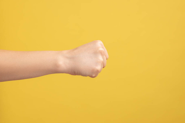 Profile side view closeup of woman hand showing boxing fists with hand, attack or defense against problems. Indoor studio shot isolated on yellow background. - Foto, afbeelding