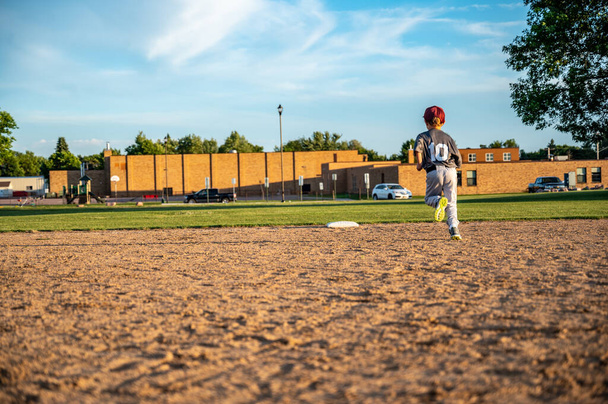 Male youth running bases after hitting the baseball. - Photo, image