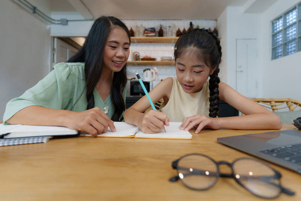 Домашняя азиатская мать и маленькая девочка учатся в онлайн-классе. Концепция электронного обучения. - Фото, изображение
