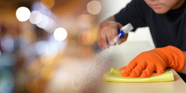 The cleaning service surface sanitizing against COVID-19 outbreak Close up view of man clean home using spray cleaning  House keeping maid cleaning service  coronavirus wearing nitrile glove - Fotó, kép