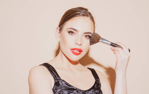 Beautiful young woman with clean fresh skin holding makeup brush. Applying tone to skin. - Photo, image