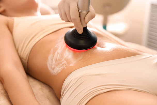 Young woman undergoing anti-cellulite treatment in beauty salon - Foto, afbeelding