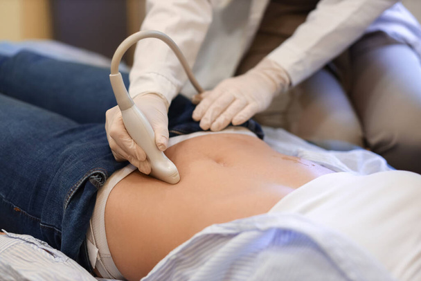 Молода вагітна жінка проходить ультразвукове сканування в сучасній клініці
 - Фото, зображення