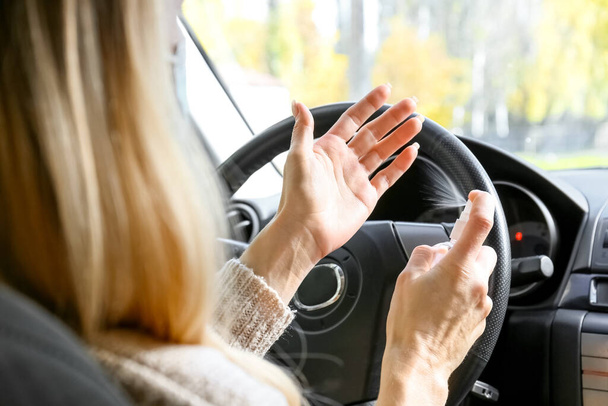 Female driver using disinfectant in car - Foto, Imagem