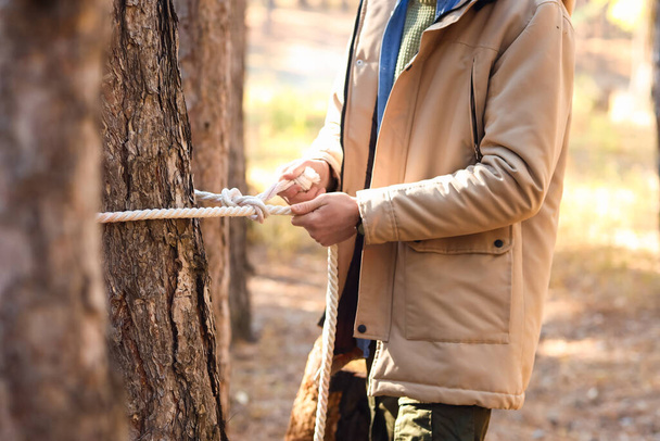 Männlicher Tourist bindet Seil an Baum im Wald - Foto, Bild