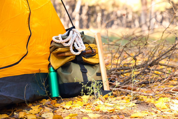 Mochila de turista con kit de supervivencia cerca de tienda en bosque - Foto, imagen
