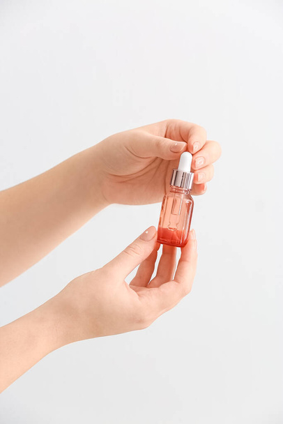 Weibliche Hände mit einer Flasche Serum isoliert auf weißem Hintergrund, Nahaufnahme - Foto, Bild