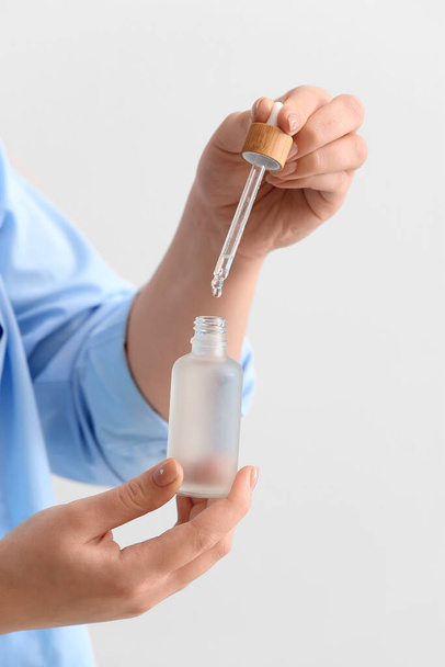 Woman with bottle of serum on white background, closeup - Photo, image