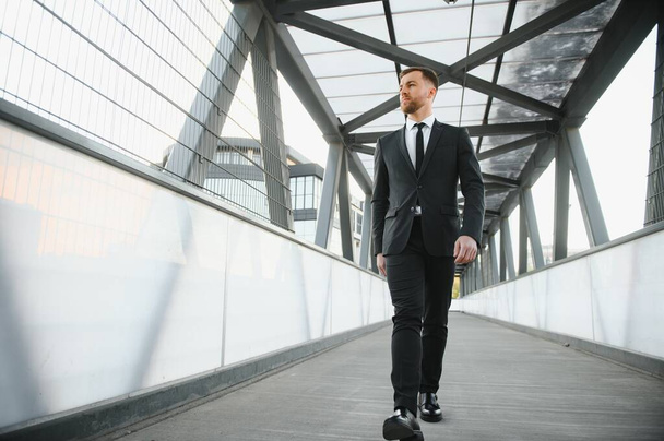 Stockbroker near the office. A successful and advanced handsome business man in a suit looks up in front of him standing on the background of concrete steps - 写真・画像