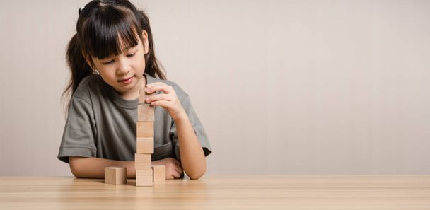 Girls build wooden cubes in layers with wooden blocks cube wooden box. girl playing with wooden block toys. Concept of early child development - Photo, Image
