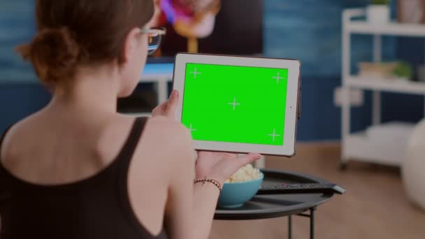 Primo piano della giovane donna con tablet digitale con schermo verde che guarda webinar seduto sul divano - Filmati, video