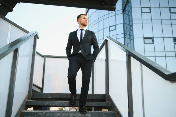 Modern businessman. Confident young man in full suit and looking away while standing outdoors with cityscape in the background. - Photo, Image