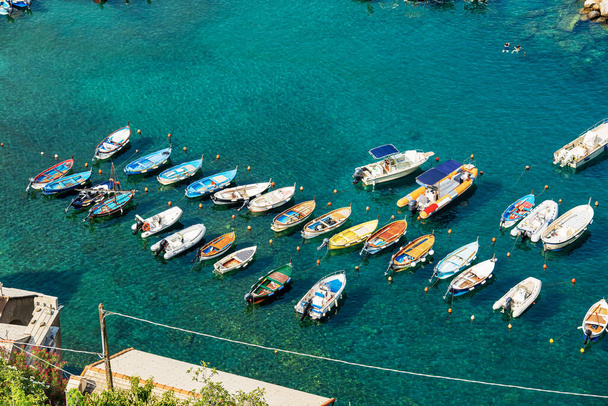 Widok z lotu ptaka na grupę małych łodzi zacumowanych w porcie starożytnej wioski Vernazza, Park Narodowy Cinque Terre, Lista światowego dziedzictwa UNESCO, Morze Śródziemne, La Spezia, Liguria, Włochy, Europa. - Zdjęcie, obraz