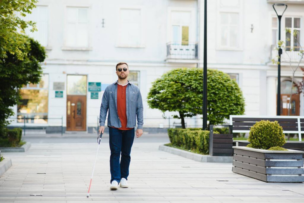 Blind Man Walking On Sidewalk Holding Stick. - 写真・画像