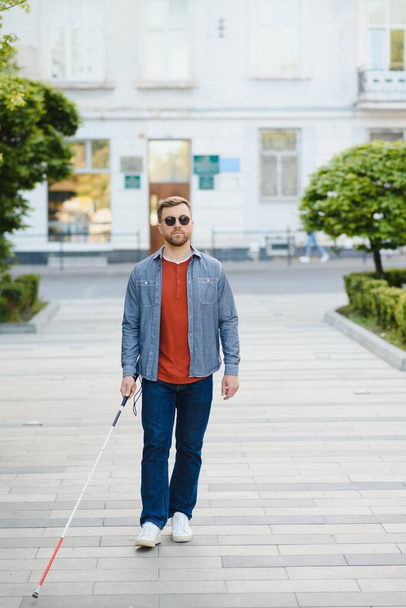 Young handsome blinded man walking with stick in town. - Φωτογραφία, εικόνα