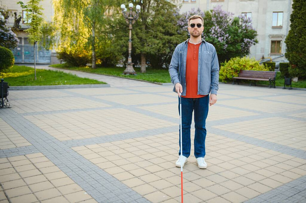 Blind man. People with disability, handicapped person and everyday life. Visually impaired man with walking stick - Фото, изображение