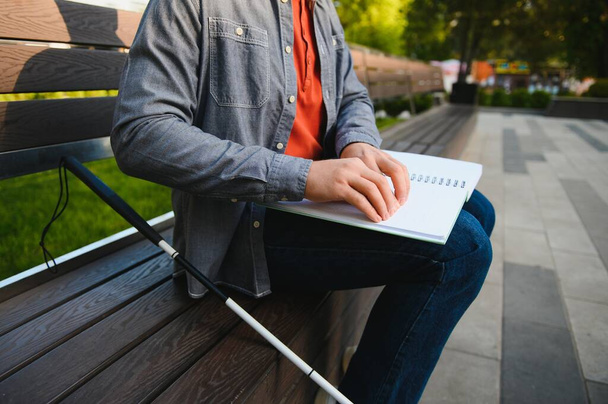 Blind man reading book on bench in park. - Foto, imagen