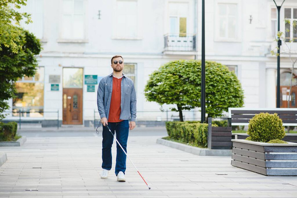 Blind man. People with disability, handicapped person and everyday life. Visually impaired man with walking stick - Fotografie, Obrázek