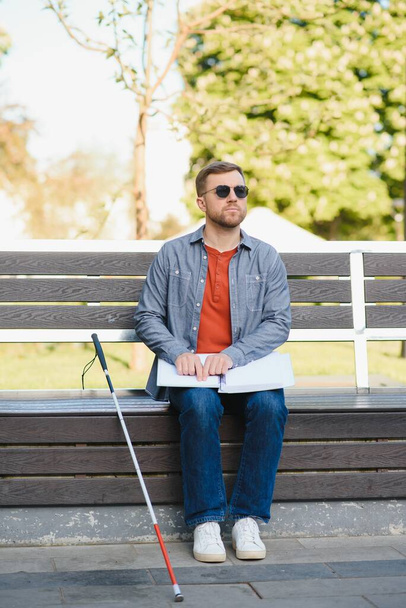 Blind man reading braille book, sitting on bench in summer park, resting. - Fotografie, Obrázek