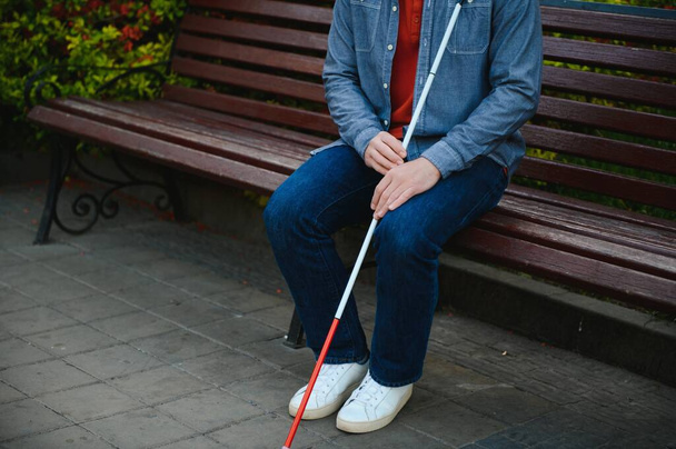 Visually impaired man with walking stick, sitting on bench in city park. Copy space. - Φωτογραφία, εικόνα