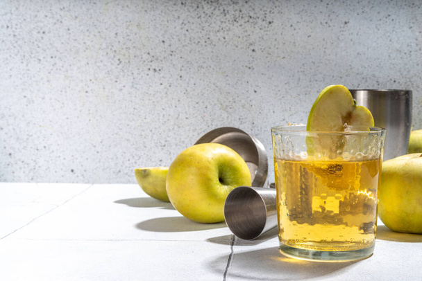 Яблочный сидр. Коктейль из яблочного уксуса, украшенный яблочным ломтиком, посудой для бара, копировальным пространством - Фото, изображение