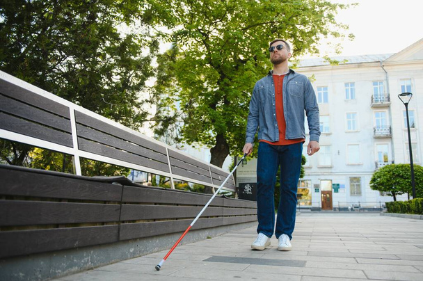 Young handsome blinded man walking with stick in town. - Foto, Bild