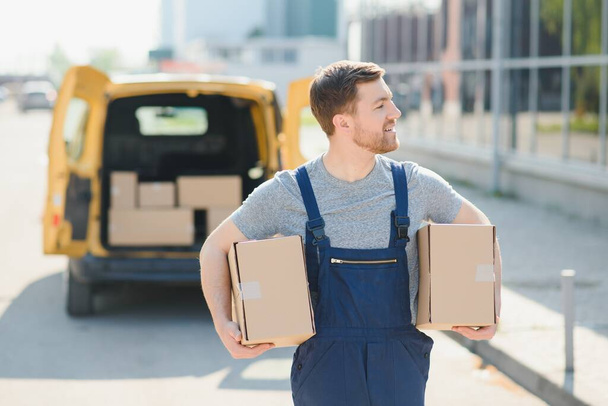 Courier service for the delivery of goods. Express service a man in a uniform delivers boxes. The employee carries the order home to the client - 写真・画像