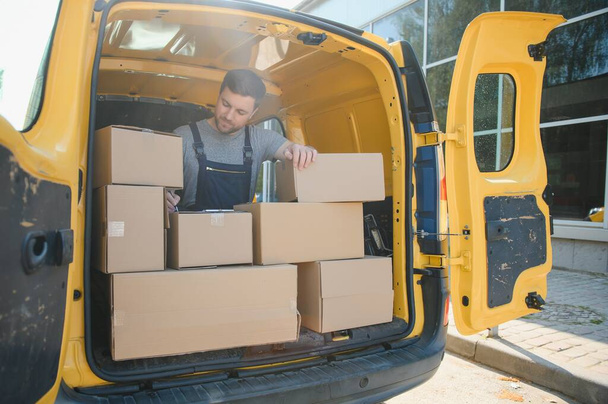 Delivery men unloading moving boxes from car. - Fotoğraf, Görsel