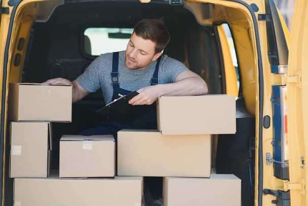 Delivery men unloading moving boxes from car. - Fotó, kép
