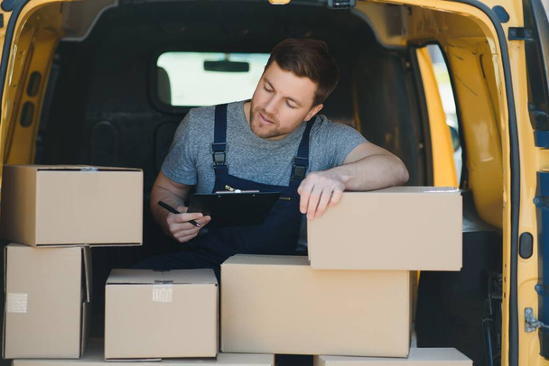 delivery service employee. Portrait of man working in delivery service. Portrait of courier with box. Courier next to minivan. Delivery service career - Fotó, kép