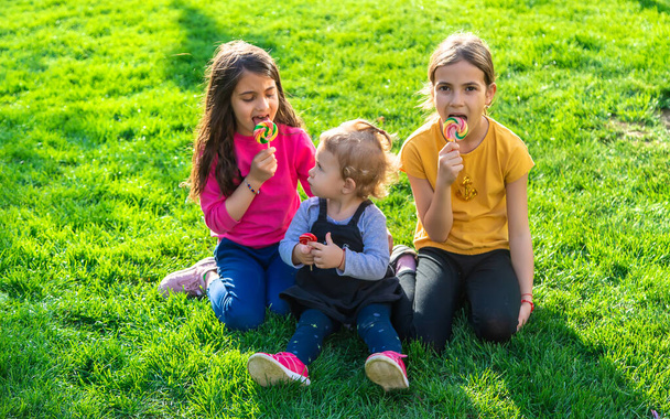 Un niño come una piruleta en el parque. Enfoque selectivo. Kd. - Foto, Imagen