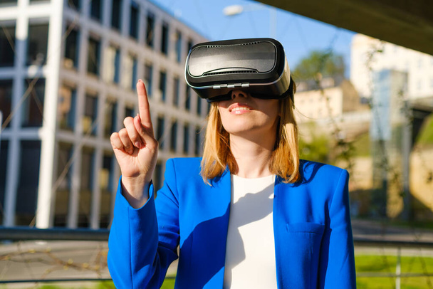 Женщина касается воздуха пальцем в очках виртуальной реальности. - Фото, изображение