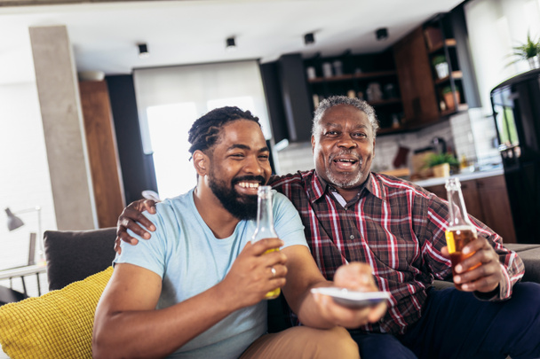 Izgatott öreg apa és fia tv-t néz, sört iszik, otthon szórakozik - Fotó, kép