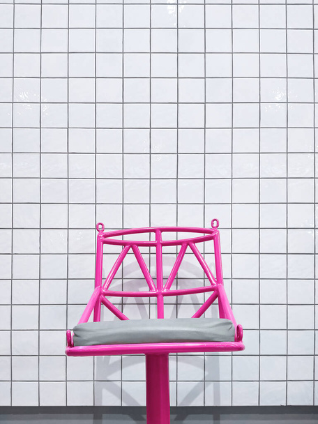 Fondo de la moderna silla de barra de metal rosa en la pared de baldosas blancas en estilo minimalista y marco vertical - Foto, Imagen