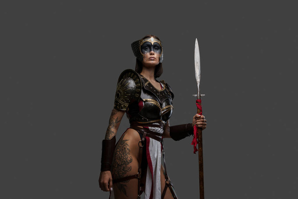 Mujer salvaje guerrera sosteniendo lanza aislada sobre fondo gris - Foto, Imagen