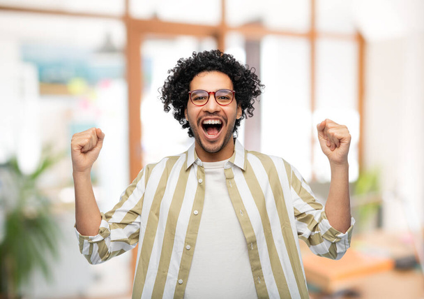 happy man in glasses celebrating victory at office - Fotó, kép