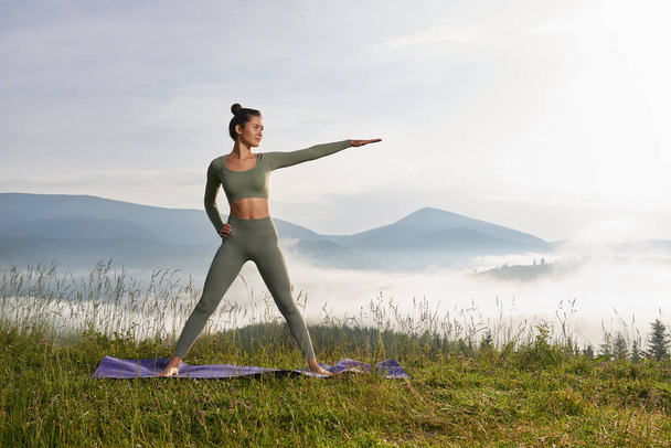 Fit young woman practicing yoga among green nature - Foto, Imagem