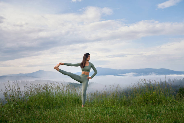 Woman in sport clothes doing flexible exercises on nature - Photo, image