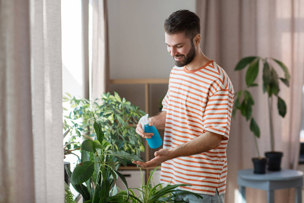 man spraying houseplant with water at home - 写真・画像