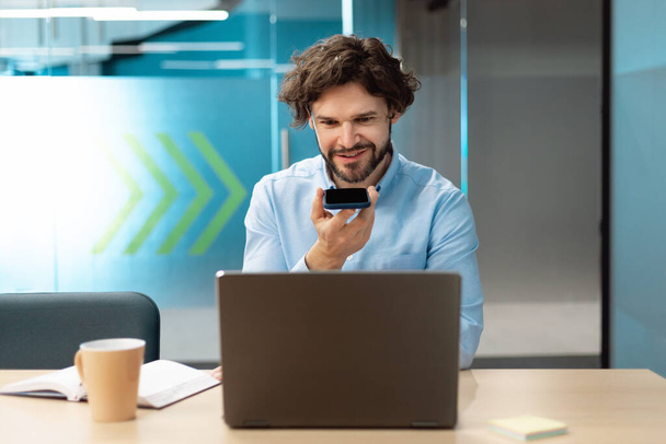 Усміхнений чоловік працює і розмовляє по телефону в офісі
 - Фото, зображення