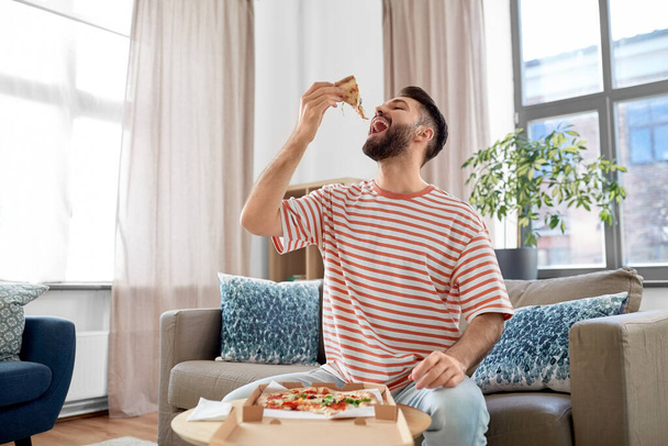 happy man eating takeaway pizza at home - Фото, изображение