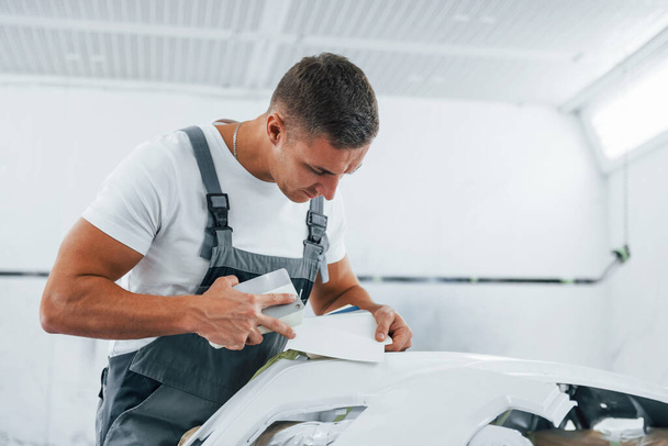 Detailed work. Caucasian automobile repairman in uniform have job in garage. - Fotó, kép