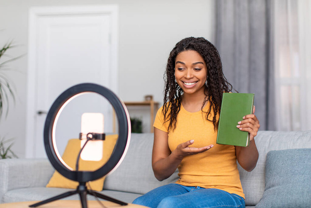 Videoblog i koncepcja technologii. Pozytywny czarny kobieta blogger nagrywanie wideo z recenzji książki w domu - Zdjęcie, obraz