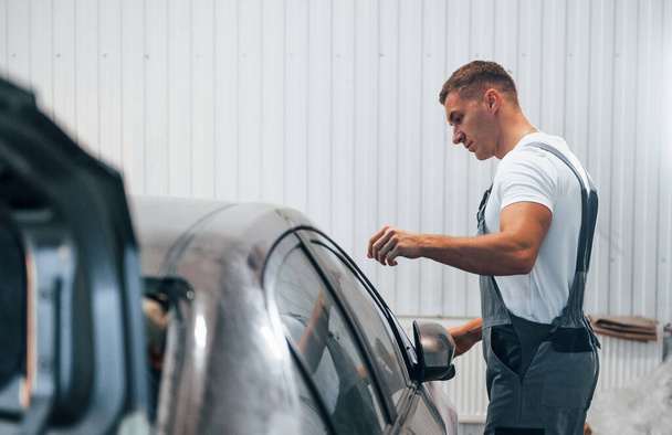 Caucasian automobile repairman in uniform works in garage. - Foto, imagen